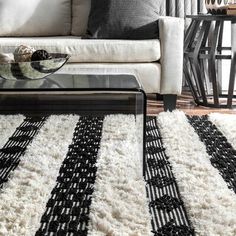 a living room with a couch, coffee table and rugs on the floor in front of it