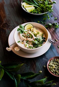 two bowls filled with food sitting on top of a wooden table next to green plants