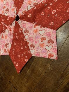 a red and pink heart shaped umbrella on top of a wooden floor with hearts all over it