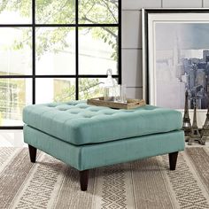 a blue ottoman sitting on top of a rug in front of a window with the eiffel tower in the background