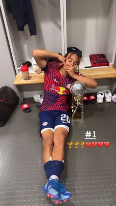 a woman laying on the ground in front of a locker room holding a soccer ball