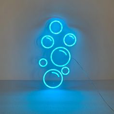 a blue neon sign with bubbles in the shape of a tree on a white wall