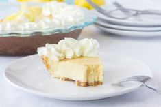 a slice of cheesecake with whipped cream on top sits on a plate next to the rest of the pie