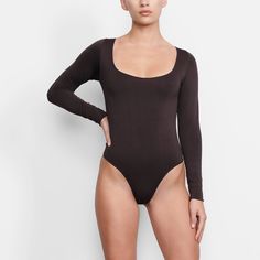 An ultra-chic and flattering long sleeve bodysuit that is made to be a staple in your wardrobe. Features a raw cut scoop neckline and a light level of compression. Fall Bodysuit With Thumbholes And Minimal Stretch, Sleek Bodysuit With Thumbholes For Fall, Fitted Bodysuit With Thumbholes And Scoop Neck, Fitted Scoop Neck Bodysuit With Thumbholes, Fitted Scoop Neck Bodysuit For Fall, Scoop Neck Bodysuit, Long Torso, Body Suit, Long Sleeve Bodysuit