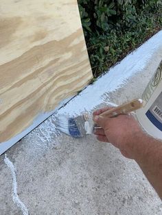 a man is painting the outside of a house with white paint and wood planks