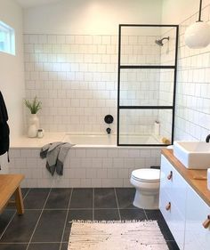 a bathroom with black and white tile flooring next to a bathtub, toilet and sink