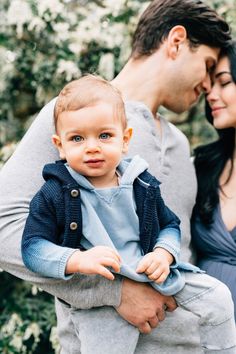 a man and woman holding a baby in their arms