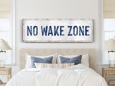 a bedroom with a bed, two lamps and a no wake zone sign on the wall