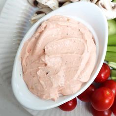 a white bowl filled with dip surrounded by vegetables