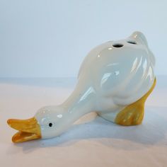 a white ceramic bird with yellow feet sitting on the ground