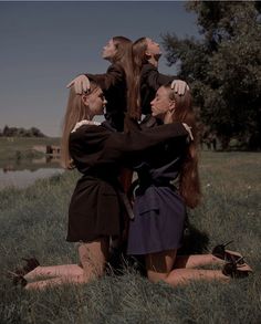 three women sitting in the grass with their arms around each other as they look up into the sky