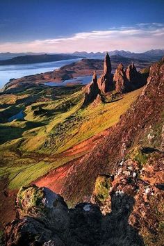 the mountains are covered in green grass and brown rocks, with blue water on each side