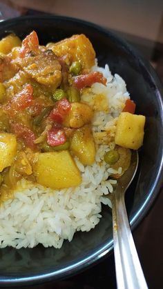 a black plate topped with rice and vegetables