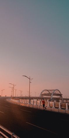 a person is walking down the road with an umbrella over their head as the sun sets