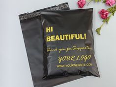 two black bags with yellow lettering on them sitting next to pink flowers and one bag has the words, beautiful thank you for supporting your logo