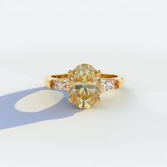 a fancy yellow diamond ring on a white surface with shadow from the light behind it