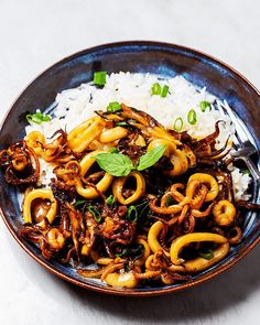 a blue plate topped with rice and octopus stir fry on top of a white table