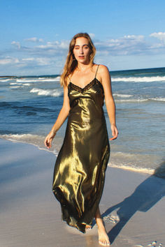 The Charlene Silk Slip Dress by Miguelina exudes timeless elegance, drawing inspiration from the glamour of the 90s. Crafted from luxurious metallic silk that shimmers beautifully in sunlight and moonlight, it features a sleek, floor-grazing silhouette perfect for grand occasions like galas and weddings, or for embracing refined luxury at home. The Charlene dress is a tribute to sophisticated craftsmanship, merging classic allure with a modern twist. Silk Slip Dress, Silk Slip, Party Looks, Metallic Colors, Gold Dress, Swim Dress