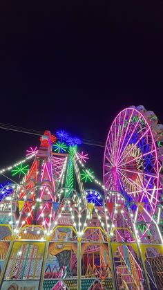 an amusement park at night with ferris wheel and lights in the dark, lit up