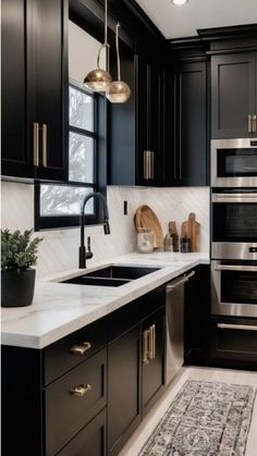 a kitchen with black cabinets, white counter tops and an area rug on the floor