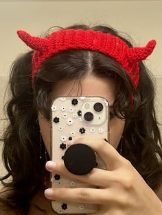 a woman taking a selfie in front of a mirror wearing devil horns and flowers