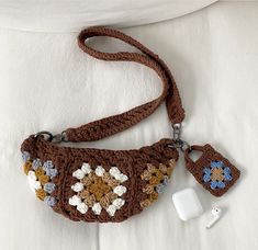 a crocheted purse and earphones on a white blanket with a pillow in the background