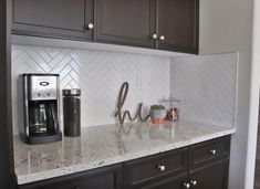 a kitchen counter with coffee maker and cups on it, next to dark wood cabinets