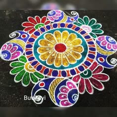 a colorful rangdi design on the ground in front of a black background with white and red