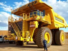 a man standing next to a large yellow dump truck