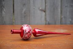 a red glass object sitting on top of a wooden table