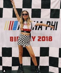 a woman standing on top of a black and white checkerboard background with her arms in the air