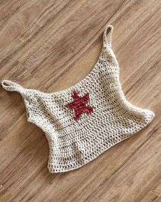 a crocheted bag with a red cross on it sitting on top of a wooden floor