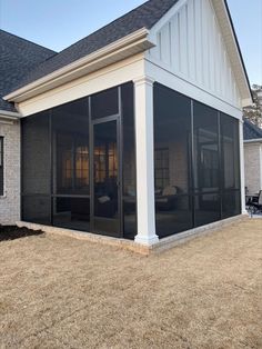 a white house with black screened porch and sliding glass doors