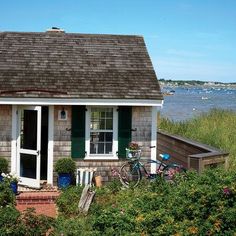 a bicycle is parked in front of a small house by the water's edge