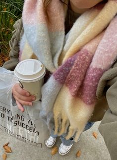 a woman holding a coffee cup and scarf