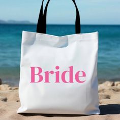 a white tote bag with the word bride printed on it sitting in the sand