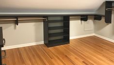 an empty room with wooden floors and black shelving units on the wall above them