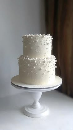 a three tiered white cake with pearls on it