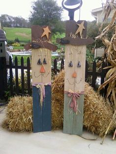 two scarecrows made out of wood are sitting on hay bales in front of a fence