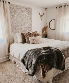 a bed with pillows and blankets on top of it in a bedroom next to two windows