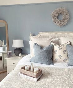 a bedroom with blue walls and white bedding has a wreath on the headboard