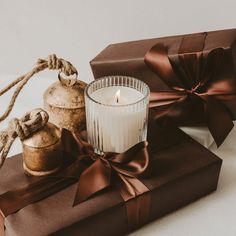 a lit candle sitting on top of a brown box next to two wrapped gift boxes