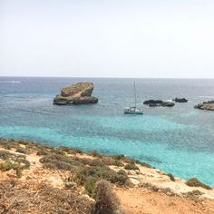 two boats are out on the water near some rocks and sand in the middle of the ocean