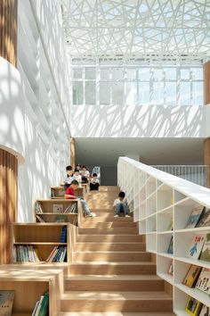 some people are sitting on the stairs in a library with bookshelves and shelves full of books