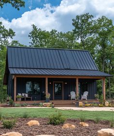 a small house with a metal roof in the middle of some trees and rocks on the ground