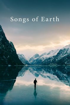 a man standing on top of a lake surrounded by mountains