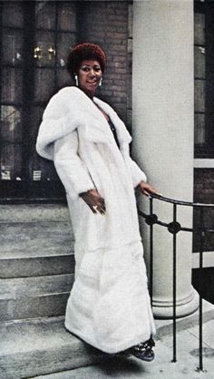 a woman in a long white coat standing on steps