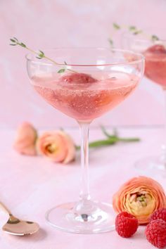 two glasses filled with raspberry martinis on top of a pink table cloth