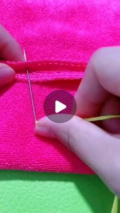 two hands are stitching together pink material