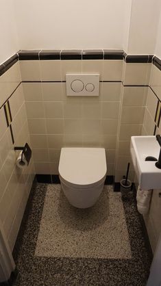 a white toilet sitting in a bathroom next to a wall mounted faucet and sink